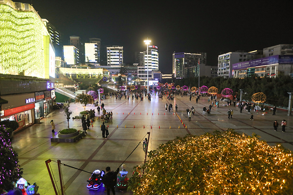 夜晚城市廣場，燈火璀璨，人流如織
